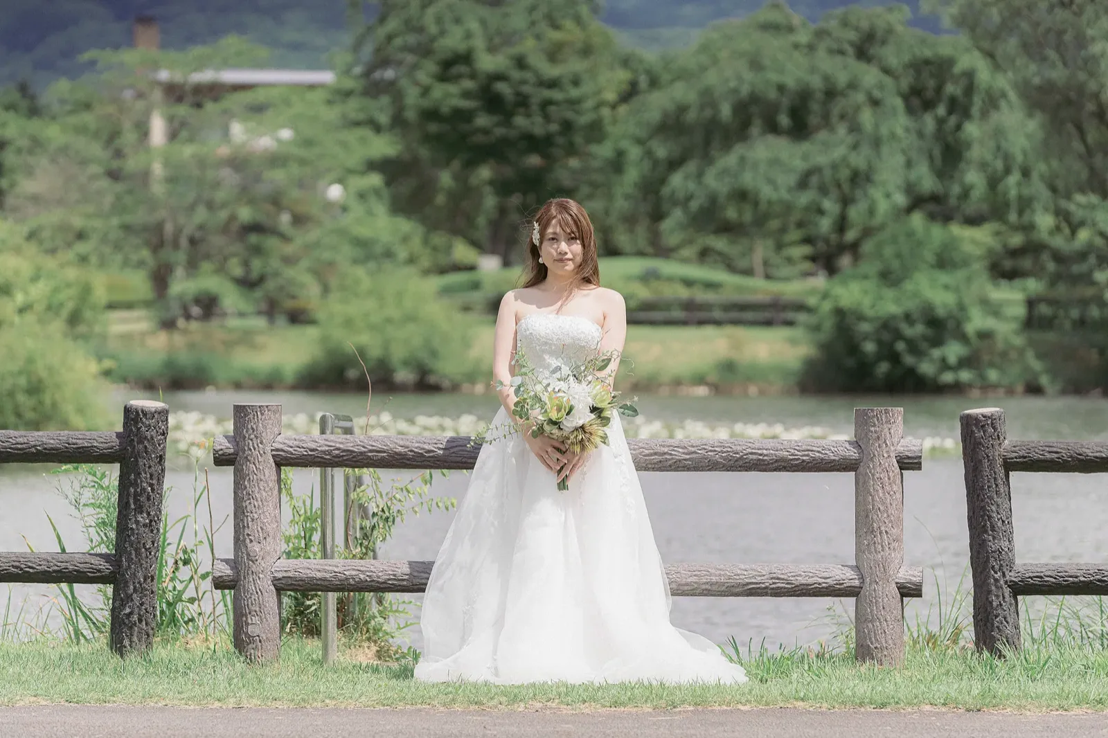 矢ヶ崎公園の池を背にブーケを持つウェディングドレスの新婦