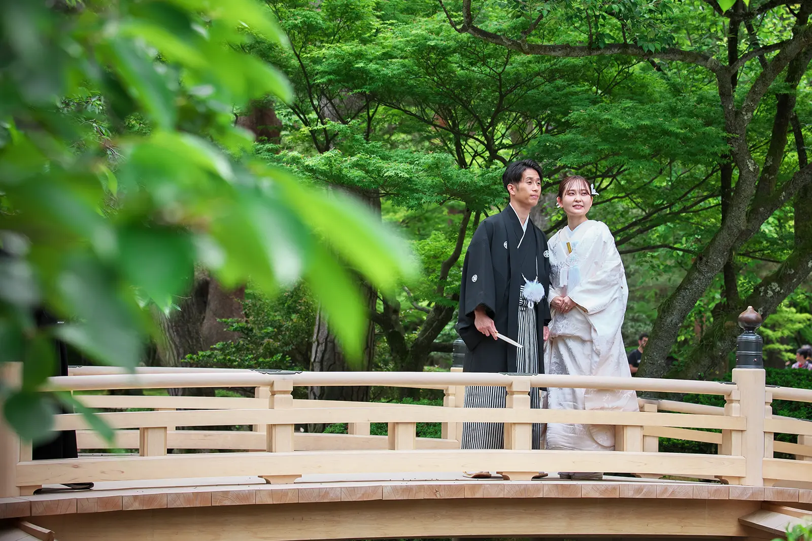 金沢の兼六園で橋の上に立つ白無垢姿の新婦と紋付袴の新郎