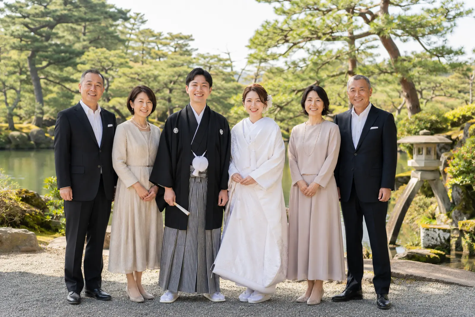 兼六園の日本庭園を背景に白無垢姿の新婦と紋付袴姿の新郎が両家の家族と並ぶフォトウェディング写真