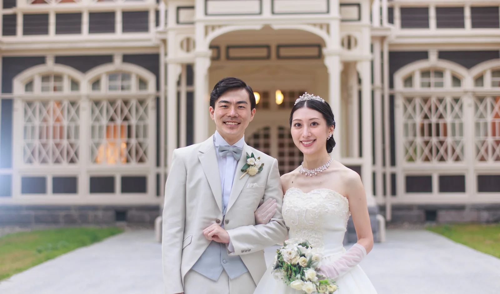軽井沢・旧三笠ホテルの玄関を背にして並ぶ洋装の新郎新婦