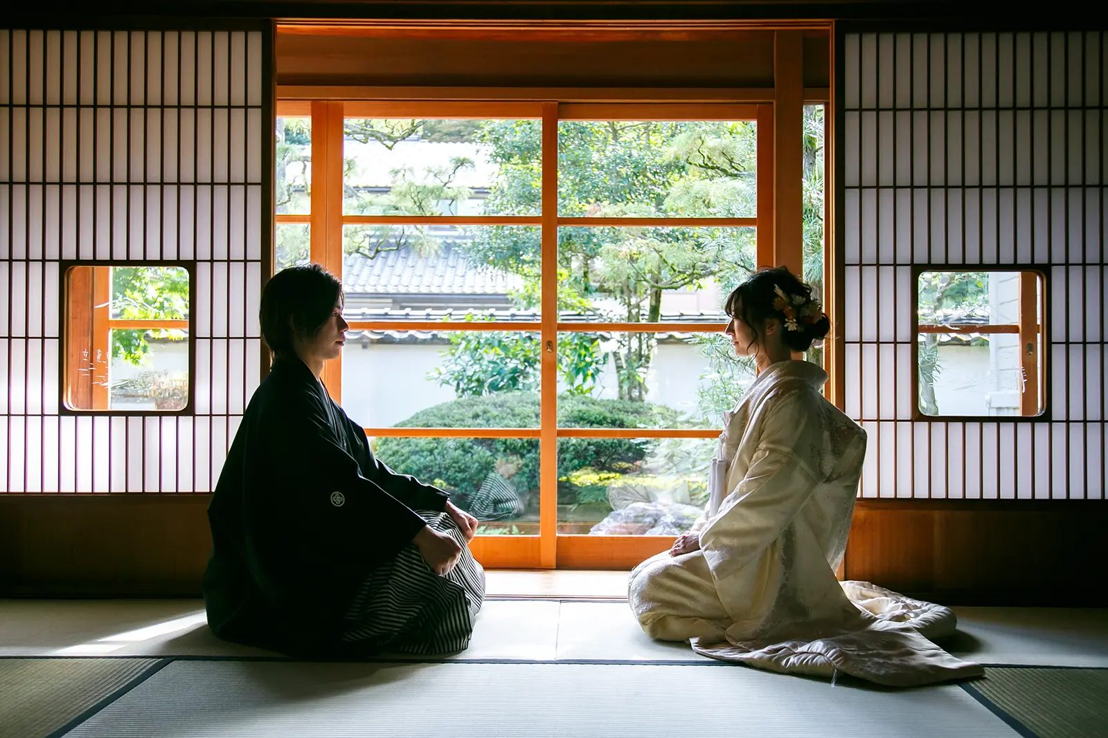 旧高峯家の和室で障子越しの庭を背景に新郎新婦が向かい合う和装フォトウェディング写真