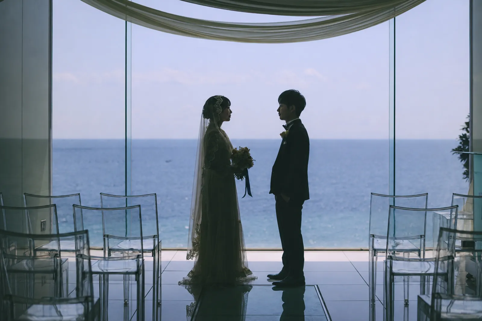 海を背景に向かい合ってファーストミートする新郎新婦
