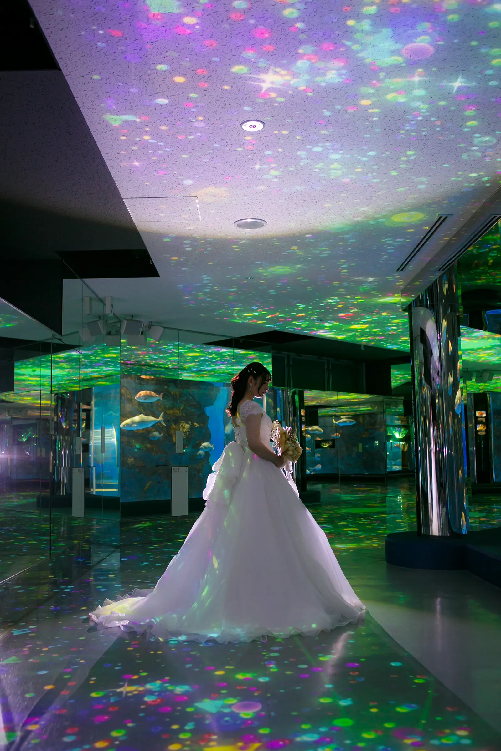 のとじま水族館の館内で光の模様に包まれて立つウェディングドレス姿の新婦