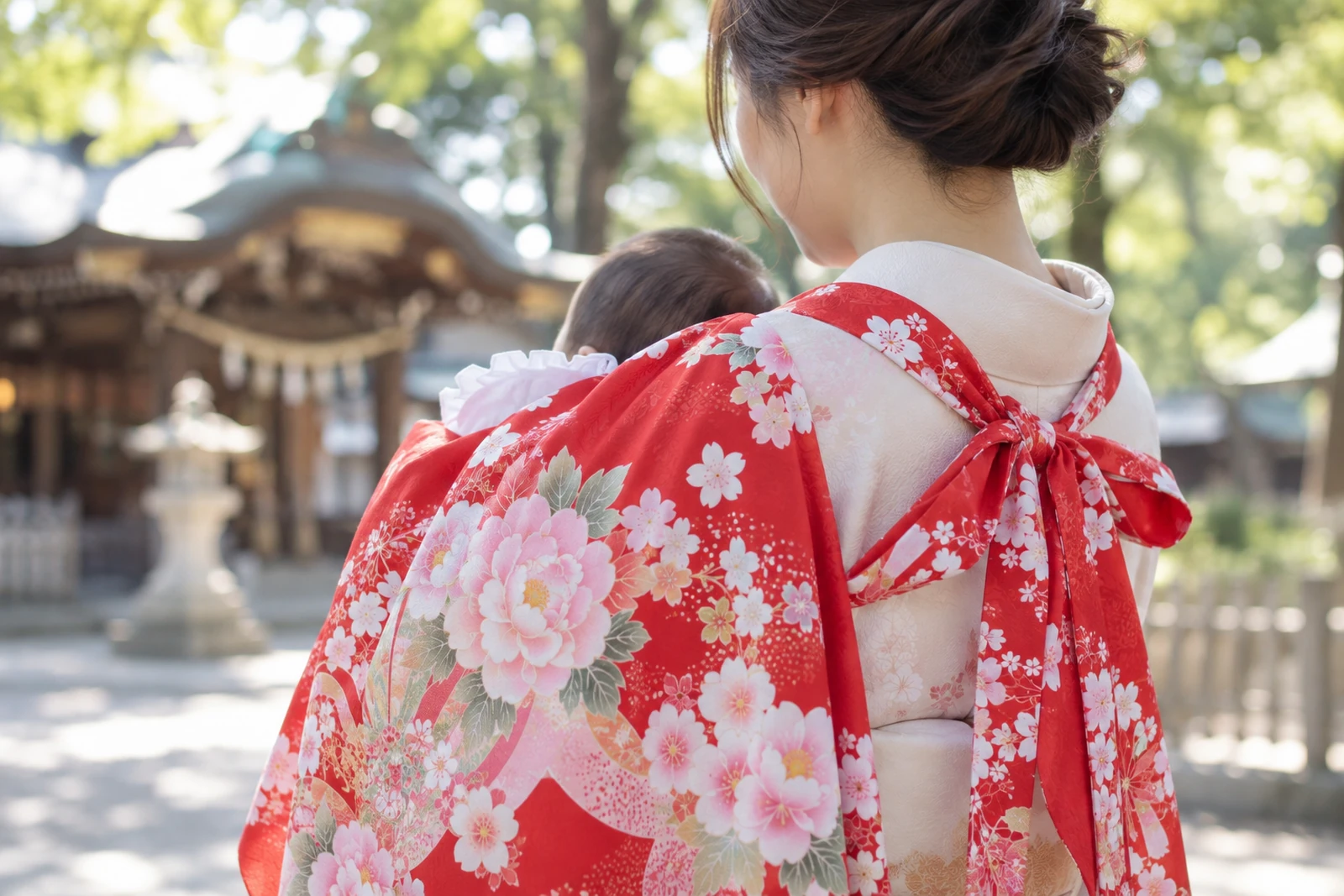 産着（祝い着）を赤ちゃんに掛け、抱く人の背中で紐を結んだ様子