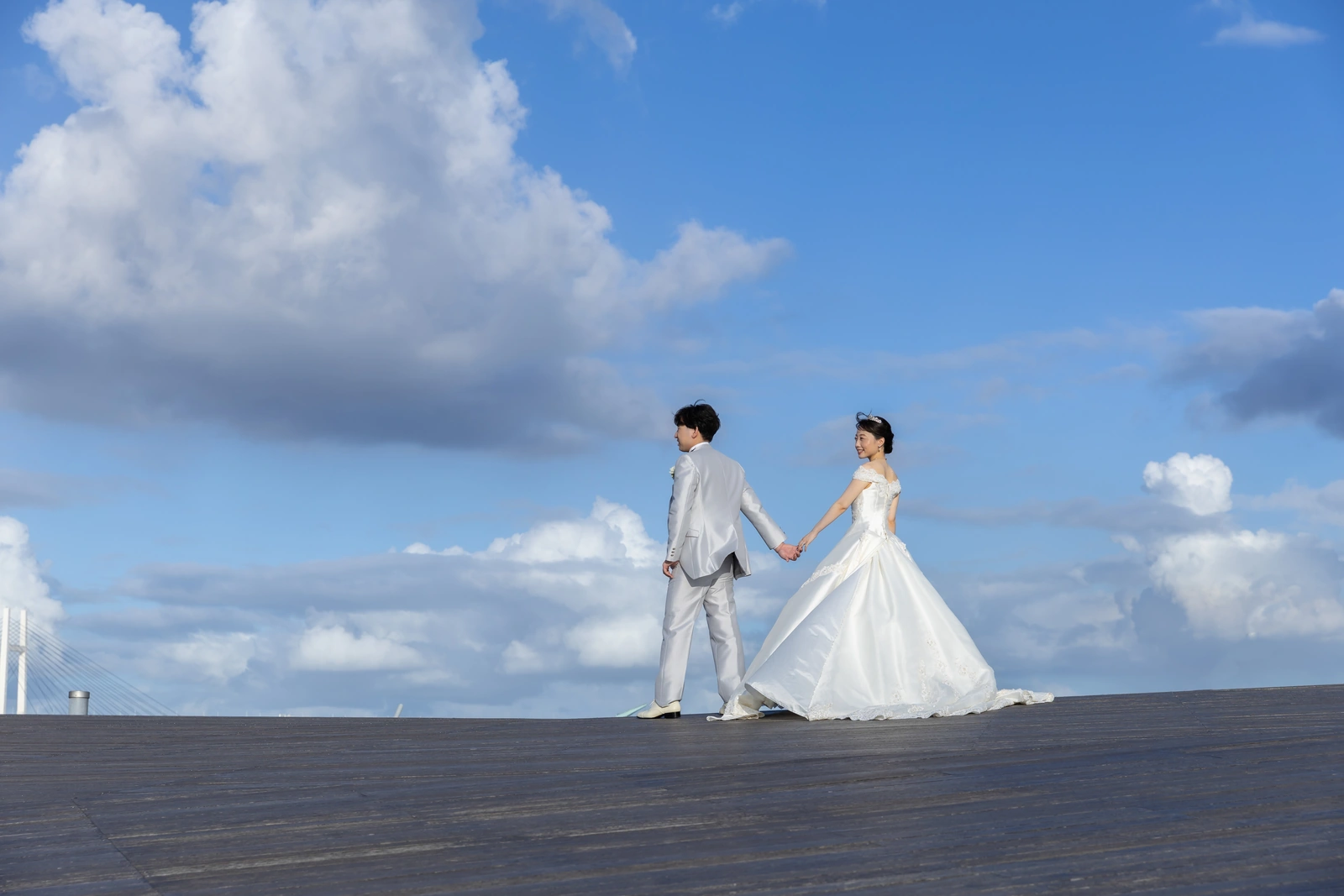横浜・大さん橋のデッキで手をつないで歩く新郎新婦の後ろ姿