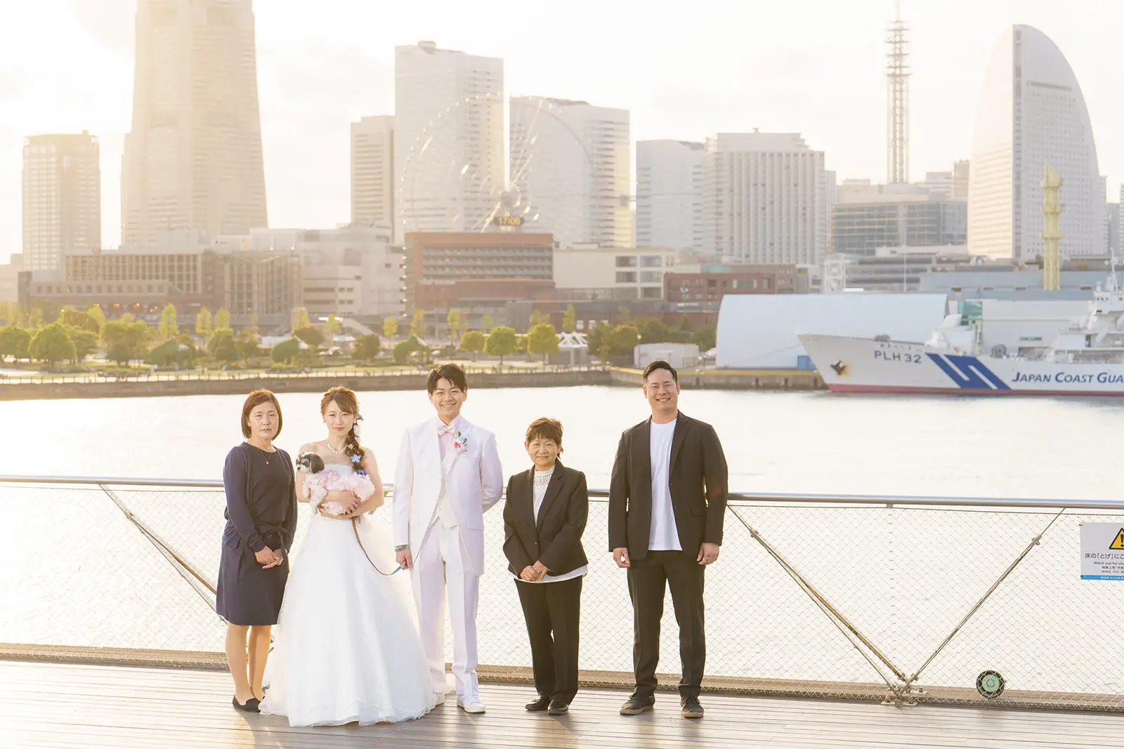 横浜の大さん橋で夕景を背景に家族と並ぶ新郎新婦