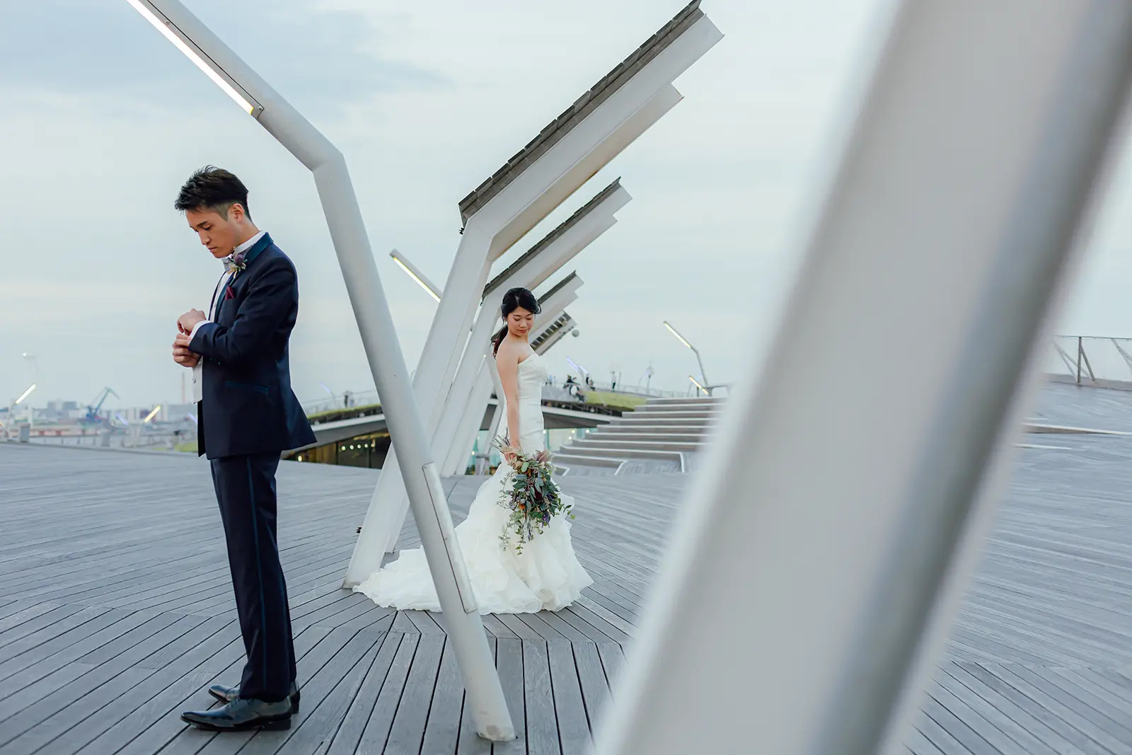 横浜の大さん橋で構造物を背景に立つ新郎新婦