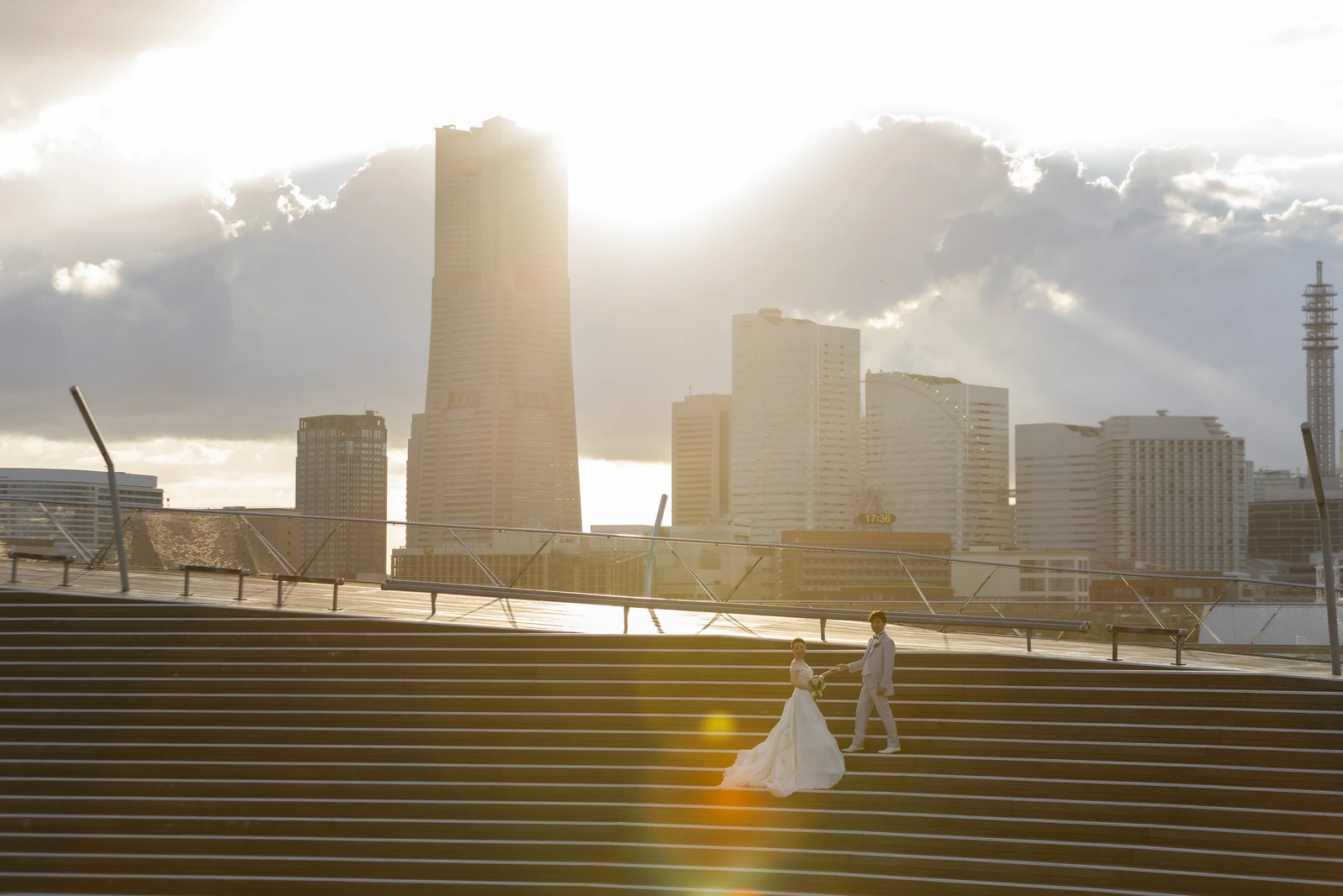 みなとみらいを背景に夕日の逆光で撮影する新郎新婦