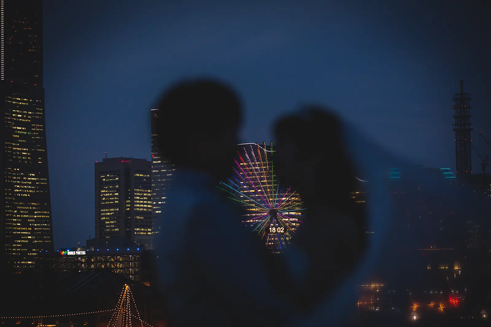 横浜の大さん橋で夜景の光を背景にシルエット風に写る新郎新婦