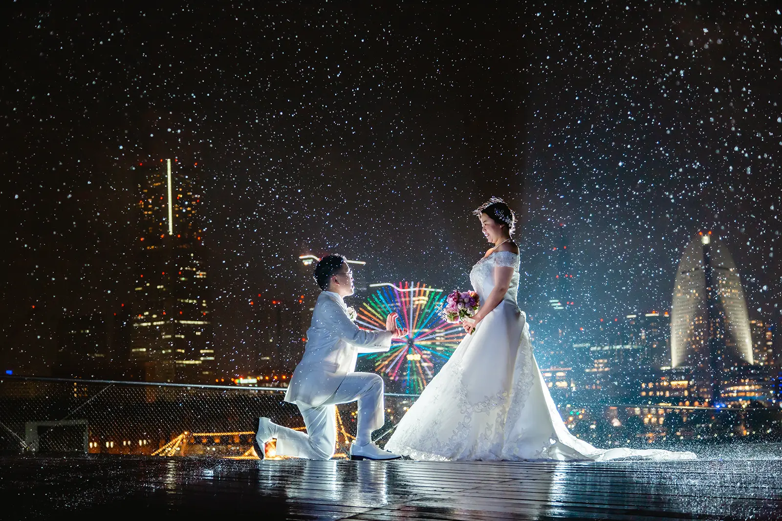 横浜の大さん橋で夜景を背景にひざまずく新郎と新婦