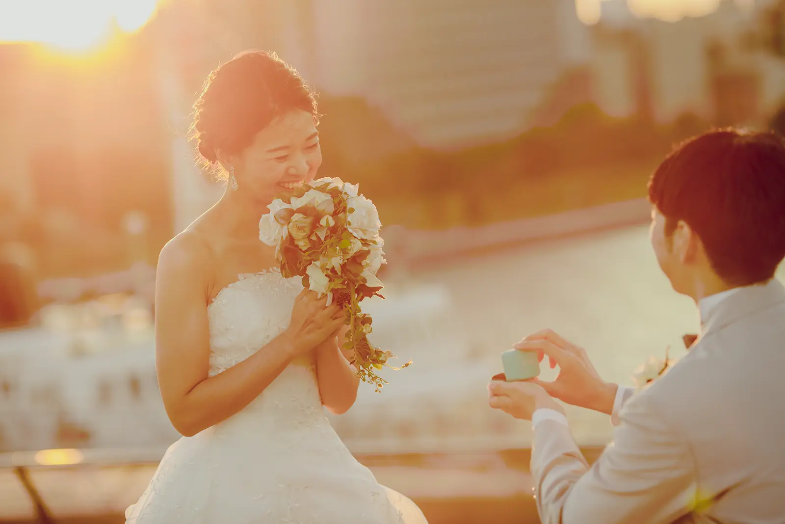 横浜の大さん橋で夕日を背景に花束を持つ新婦と新郎