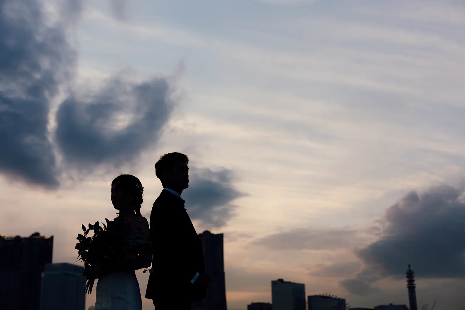 横浜の大さん橋で夕空を背景にシルエットで立つ新郎新婦