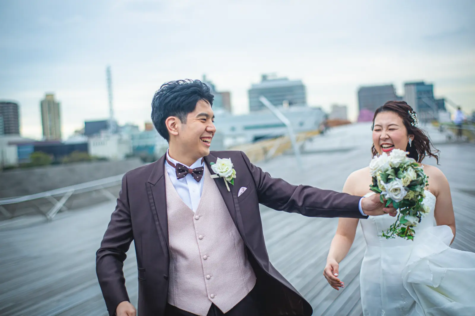 大さん橋でブーケを手に走り出す洋装の新郎新婦