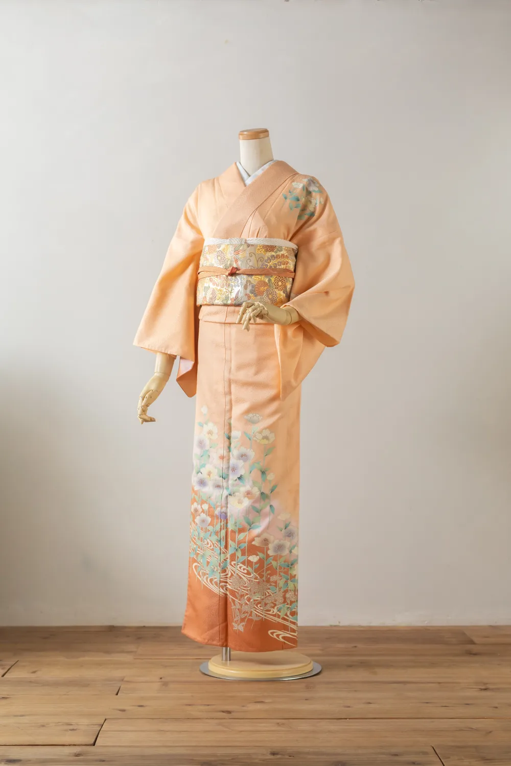 サーモンピンクの訪問着。裾に花と流水の模様、金糸の帯を合わせた全身イメージ