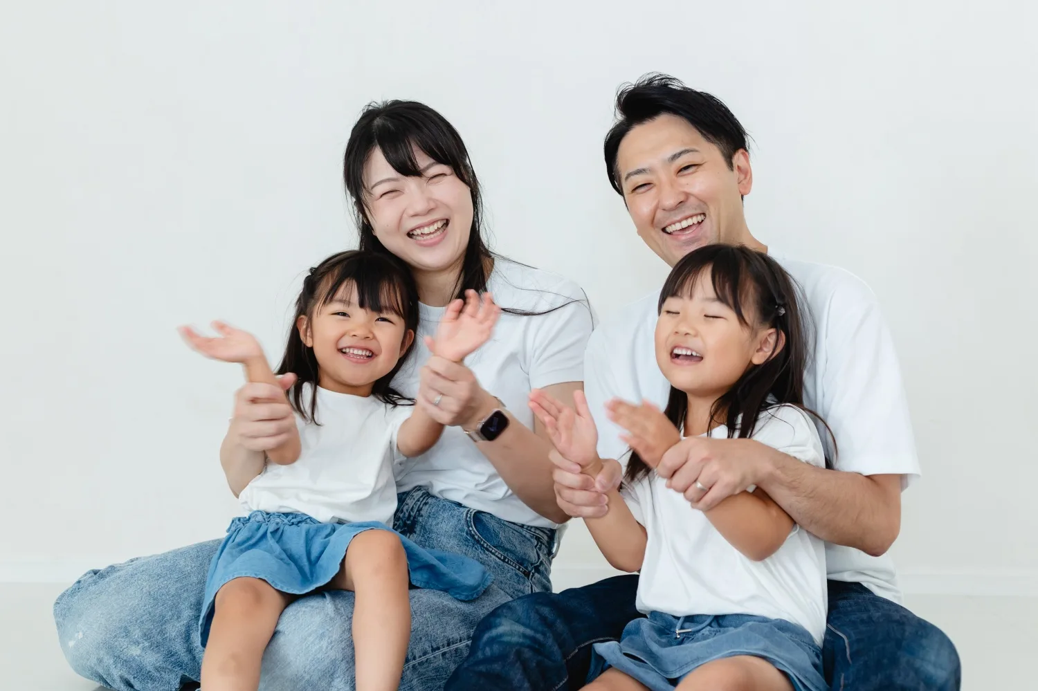 手を叩いて笑い合う家族4人。私服のままリラックスした家族写真