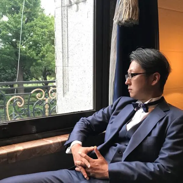 窓辺に座り外を見つめるフォトグラファーDAIのポートレート写真