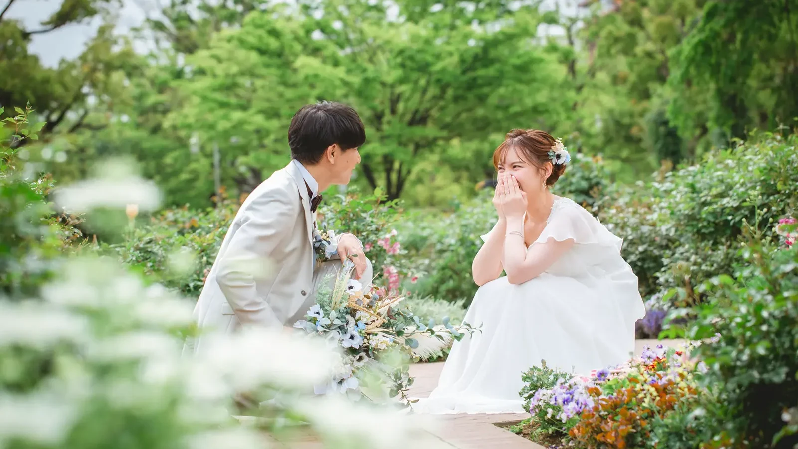 花に囲まれたガーデンで自然な笑顔を見せるお二人のフォトウェディング写真
