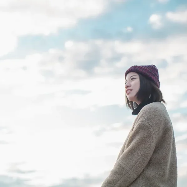 空を背景にやわらかな表情を見せるフォトグラファーSAKIのポートレート写真