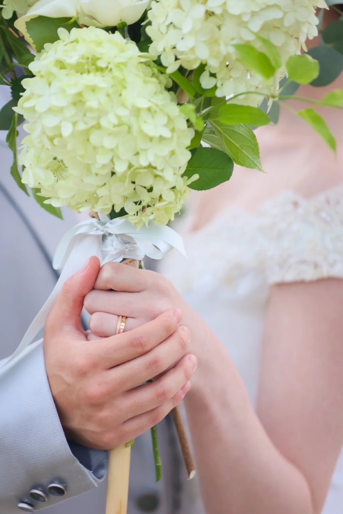重ねた手元にきらめくペアの結婚指輪と白いアジサイのブーケ｜金沢の洋装フォトウェディング