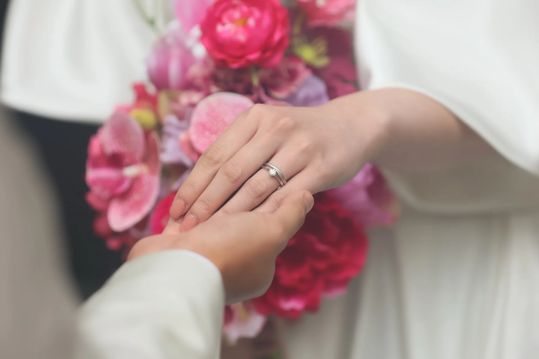 重ねた手元にきらめく結婚指輪とピンクのブーケ｜金沢のフォトウェディング（洋装ロケーション）