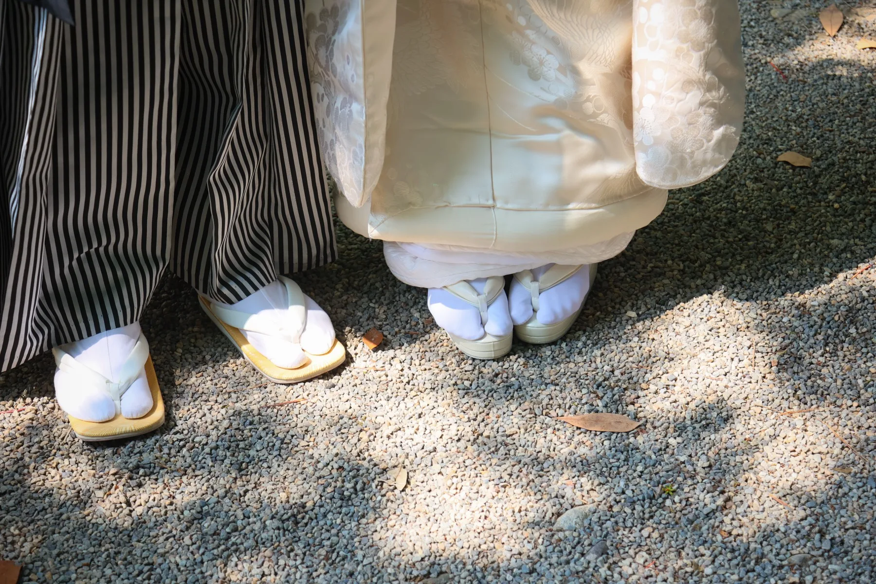 玉砂利の上に並ぶ新郎新婦の足元、白足袋に草履|金沢の和装ロケーションフォトウェディングのディテールカット