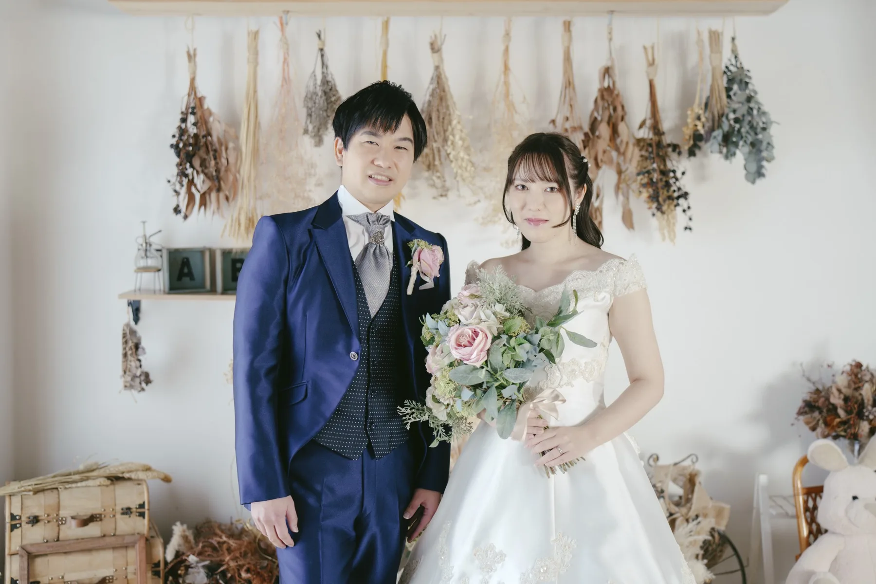 ドライフラワーを背景にブーケを持つウエディングドレス姿の花嫁と新郎｜フォトジェリッシュ横浜のマタニティフォト