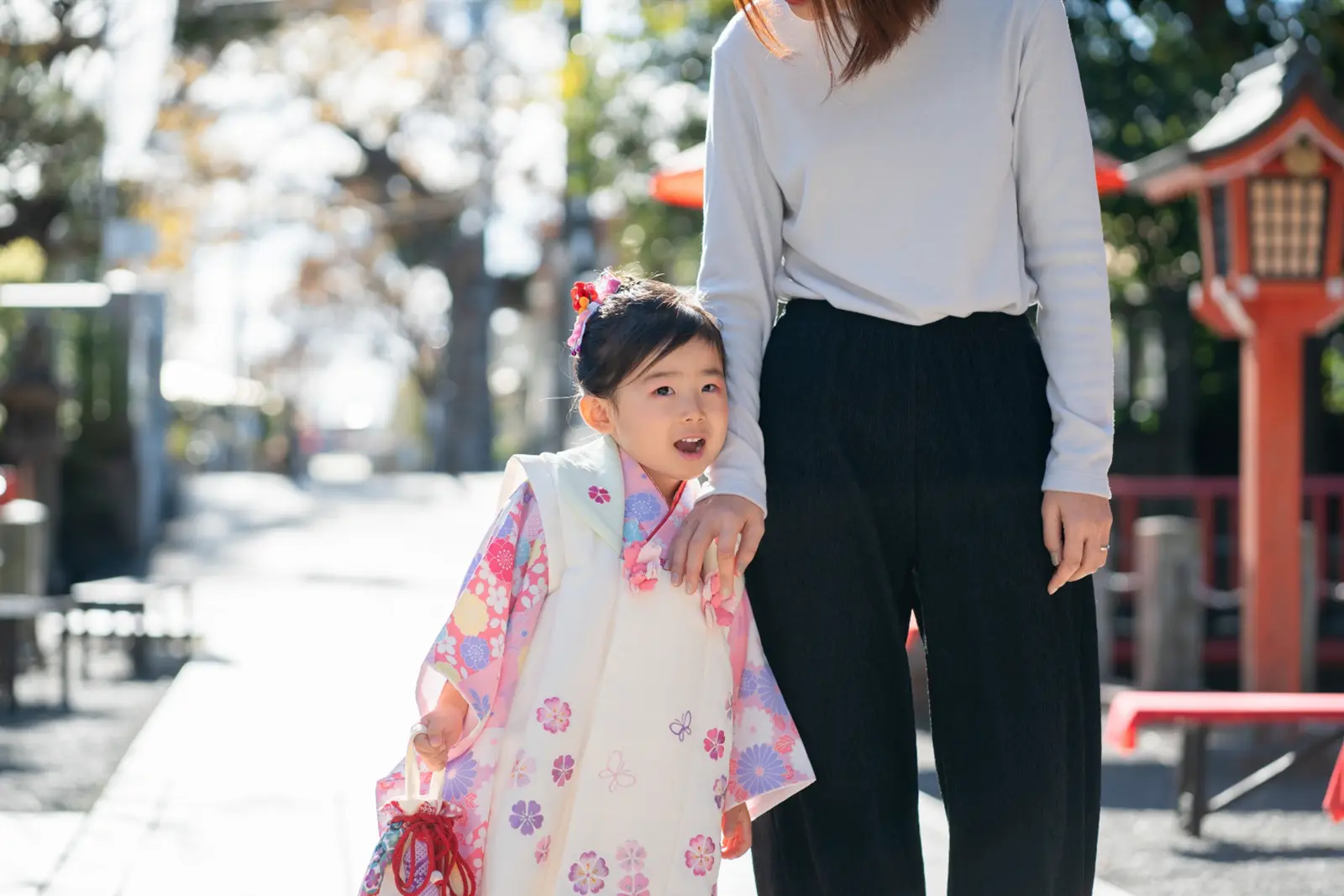 母親の手をつかんで立つ被布姿の3歳の女の子、七五三の親子写真（六所神社・大磯）