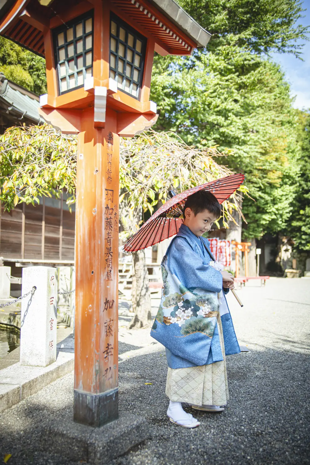 常夜灯の前で振り返る5歳の男の子、青い羽織袴の後ろ姿（七五三・六所神社）