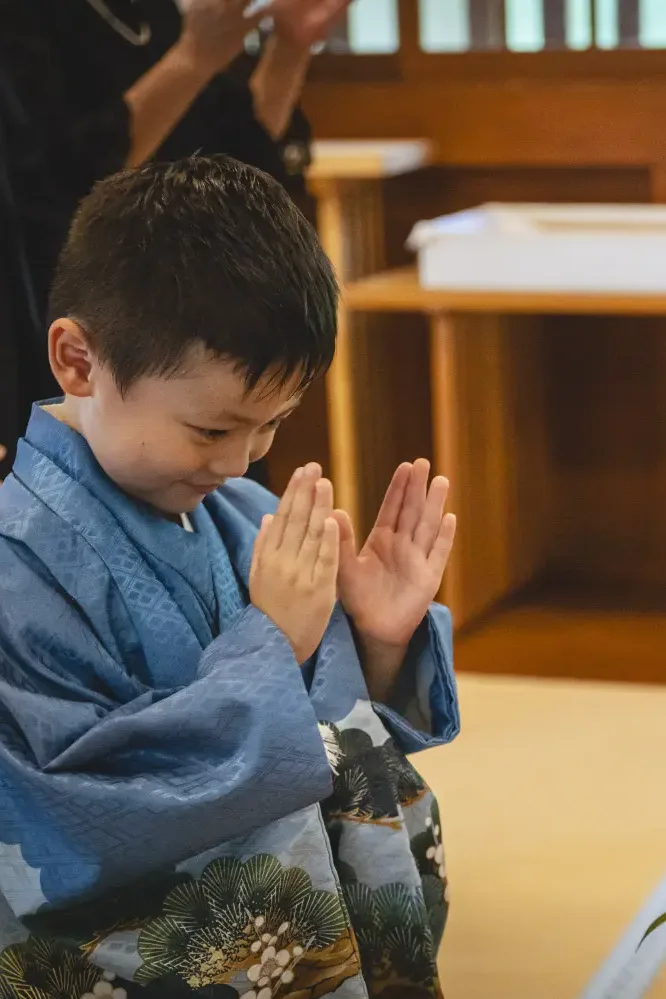 玉串を捧げたあと目を伏せて手を合わせる5歳の男の子、青い羽織袴の拝礼（七五三・六所神社）