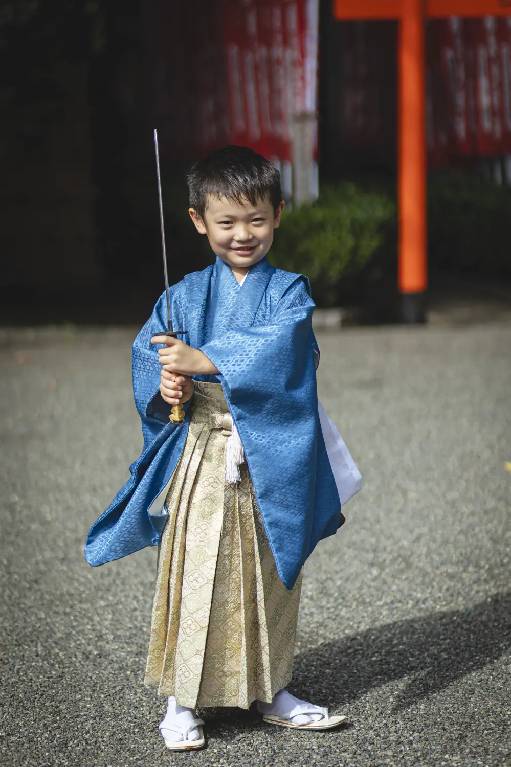 刀のかたちの小道具を正面に立てて構える5歳の男の子、青い羽織袴の全身（七五三・六所神社）
