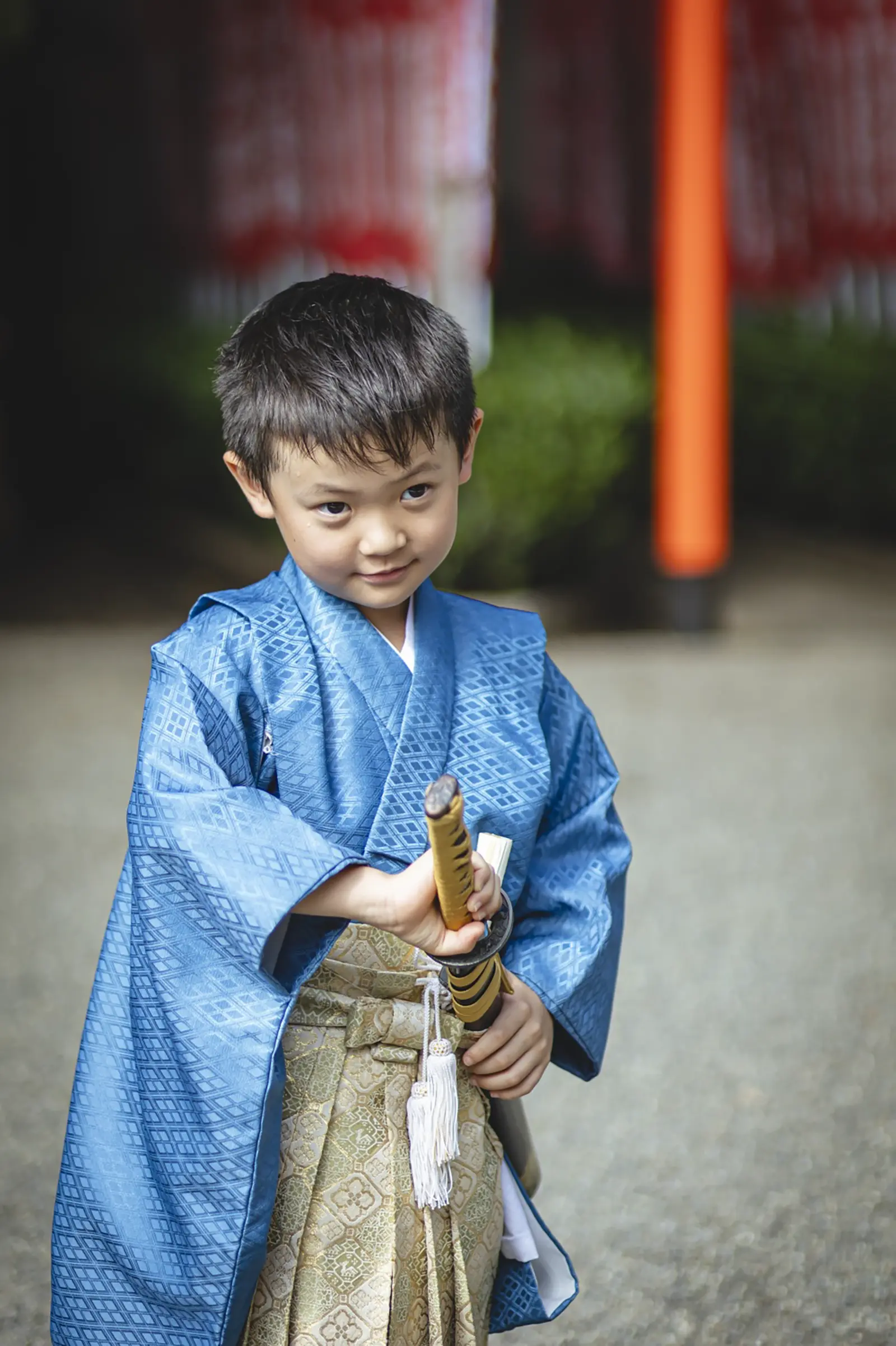 腰の小道具の柄に手をかけて得意げに笑う5歳の男の子、青い羽織袴（七五三・六所神社）