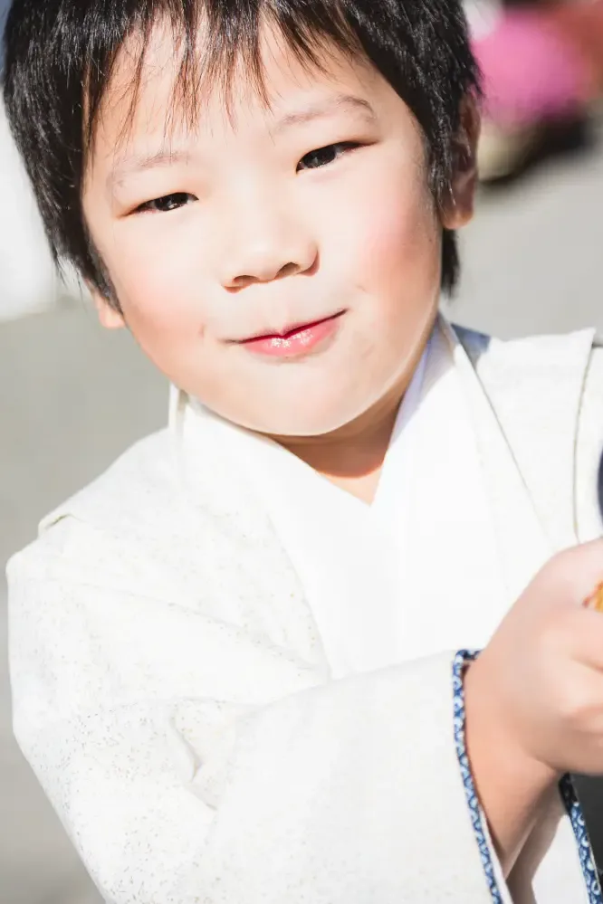 参道で得意げに口元をゆるめる5歳の男の子の表情アップ、生成りの羽織姿の七五三撮影（六所神社・大磯）