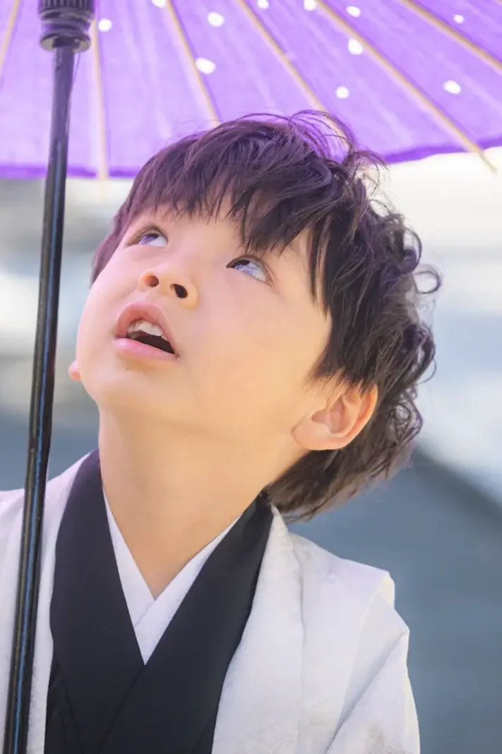 紫の和傘の内側を見上げる5歳の男の子のクローズアップ、七五三（六所神社・大磯）