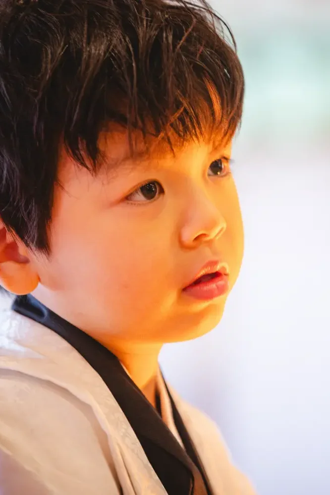 暖かな色の光を頬に受けて真剣な表情を見せる5歳の男の子の横顔、七五三（六所神社・大磯）
