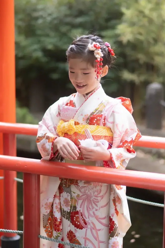 太鼓橋の欄干にもたれて手元を見つめる7歳の女の子、四つ身姿の七五三（六所神社・大磯）