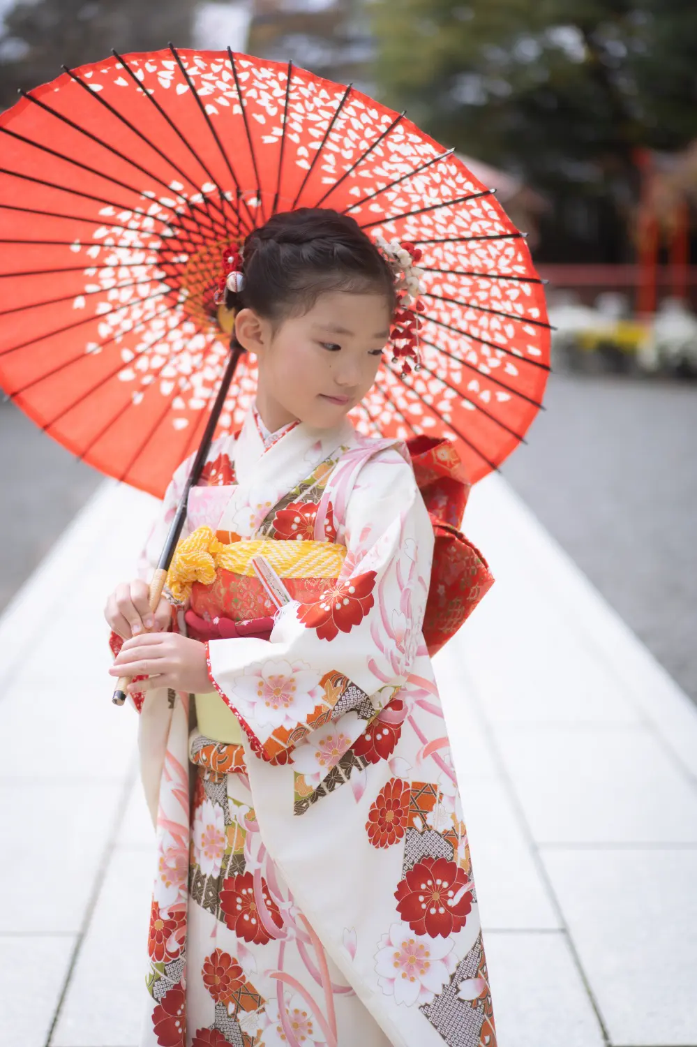 朱の和傘の下で伏し目がちにたたずむ7歳の女の子、四つ身姿の七五三（六所神社・大磯）