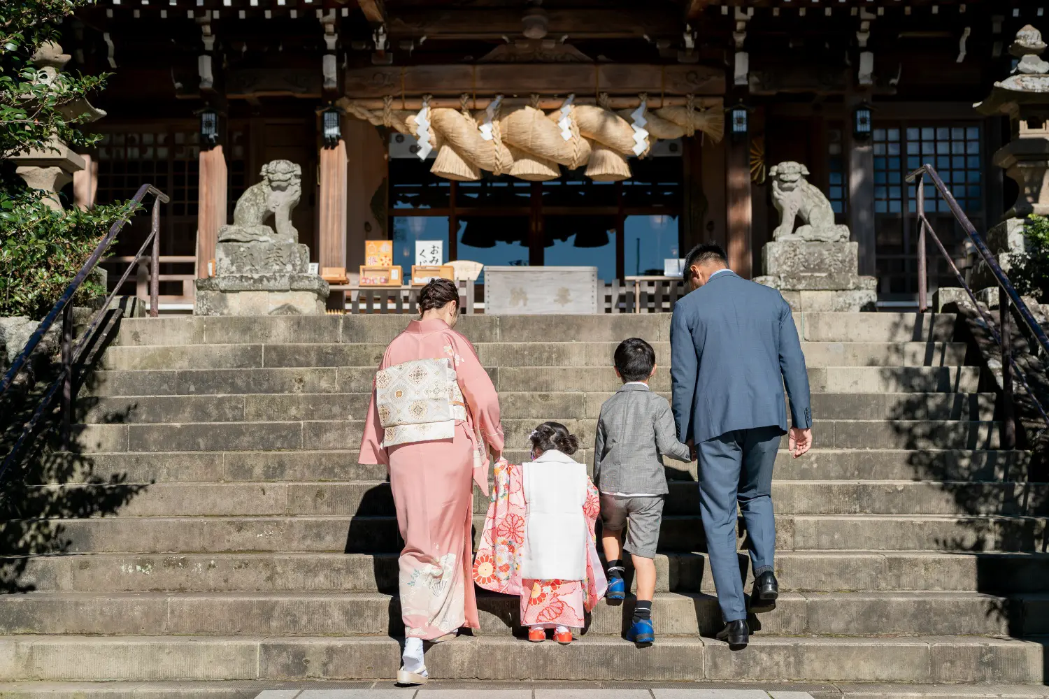 六所神社の拝殿へ続く石段を上る家族4人の後ろ姿、被布姿の3歳の女の子の七五三（大磯）