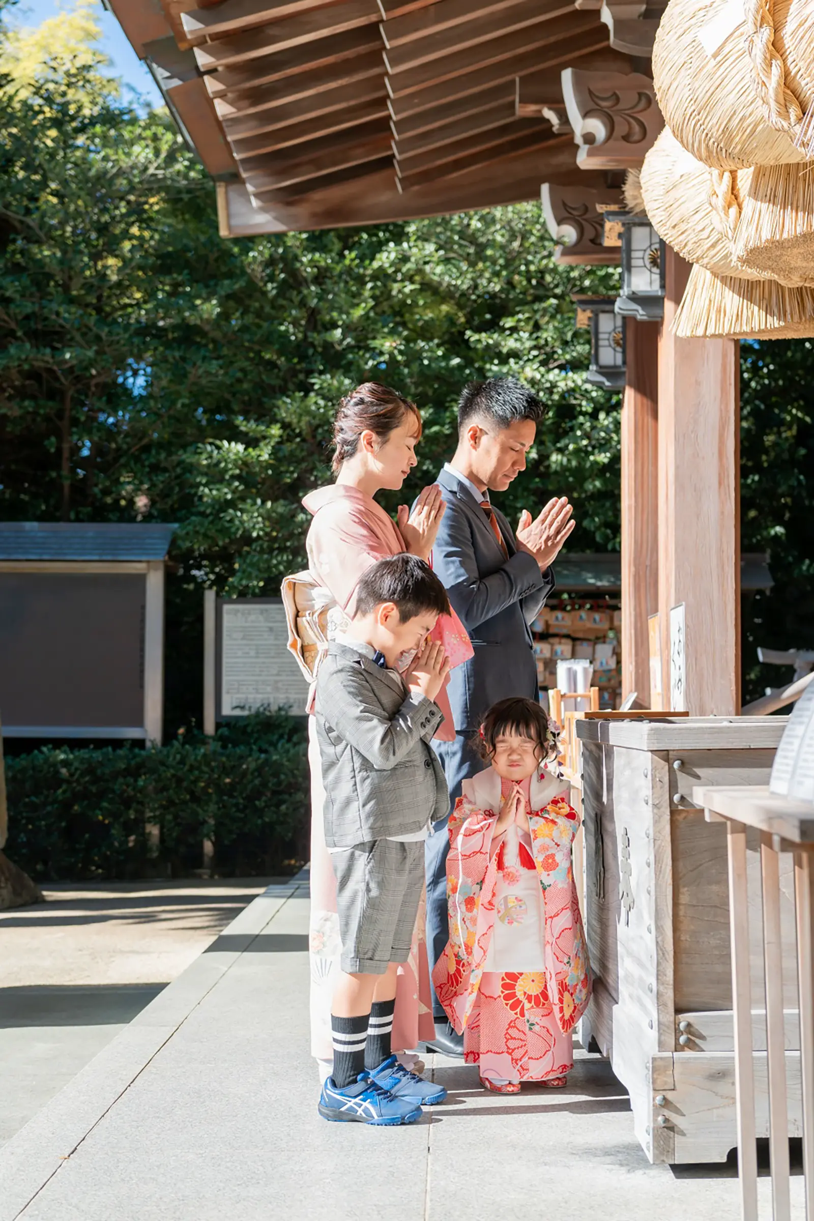 六所神社の拝殿前で手を合わせて参拝する家族4人と被布姿の3歳の女の子（大磯・七五三）