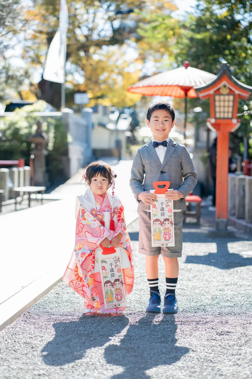 六所神社の千歳袋を持って参道に並ぶ被布姿の3歳の女の子と兄、七五三（大磯）