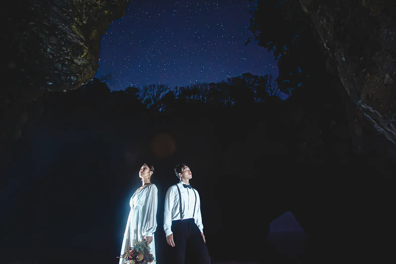 伊豆・下田の龍宮窟で星空を背景に撮影する新郎新婦