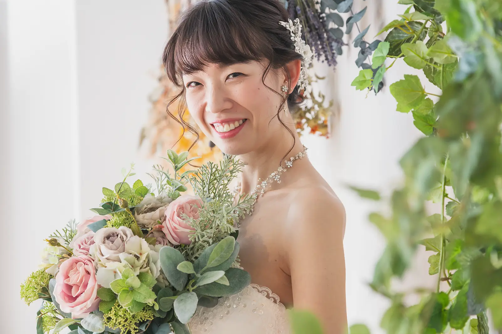 ブーケを持って笑顔を見せる新婦のソロポートレート写真