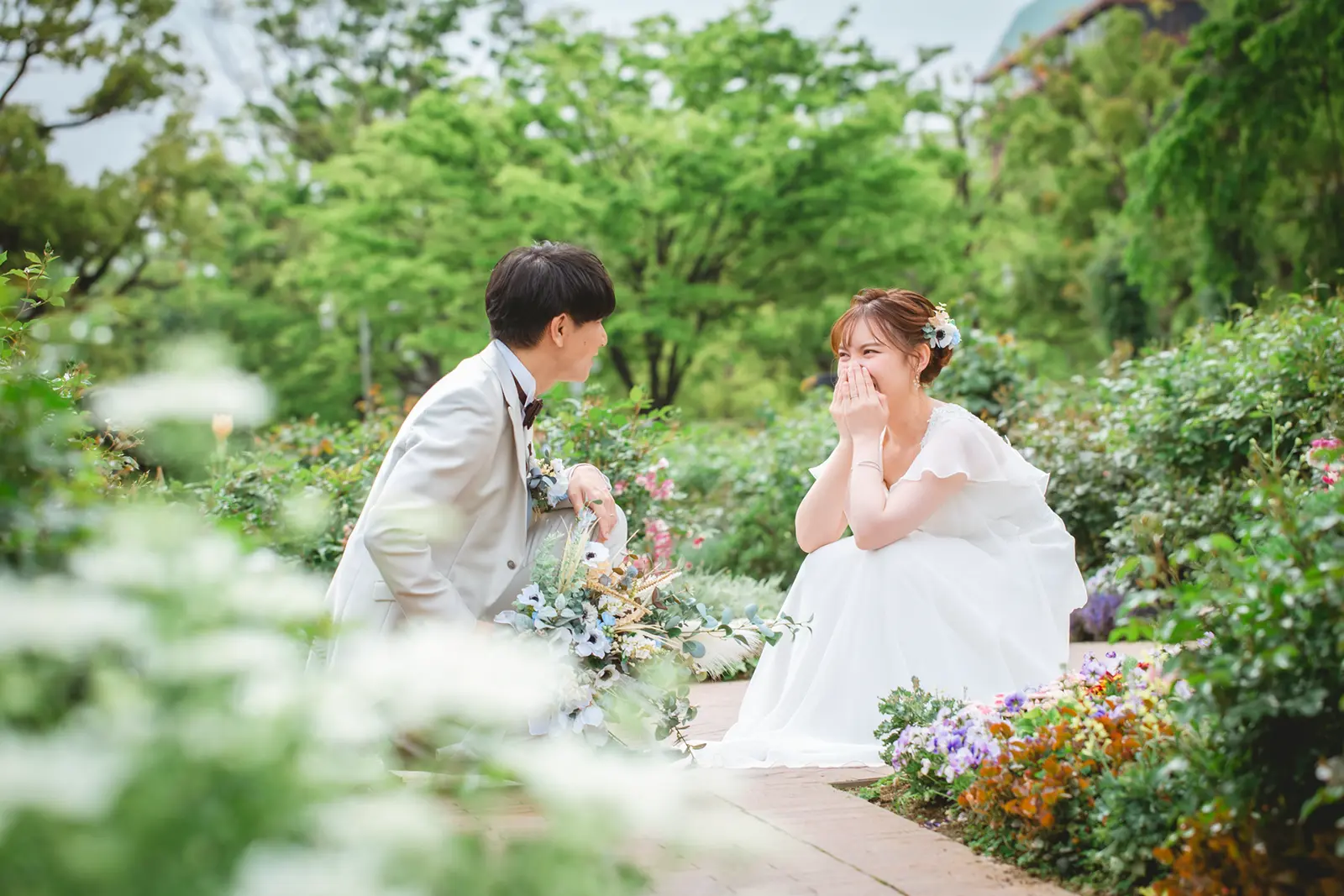 花に囲まれた山下公園のガーデンで笑い合う新郎新婦のフォトウェディング写真