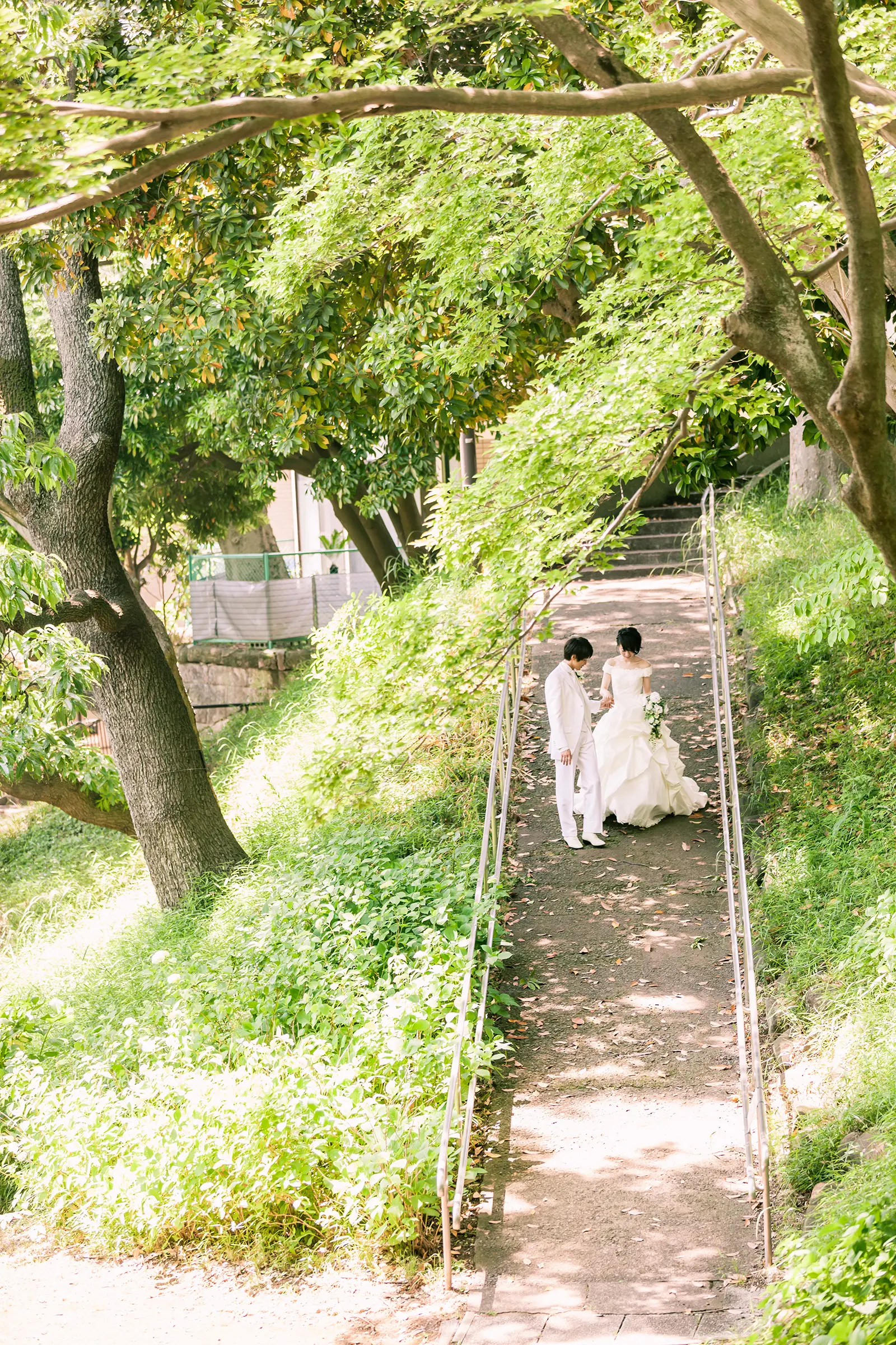緑に囲まれた坂道で向かい合う新郎新婦を写したフォトウェディング写真