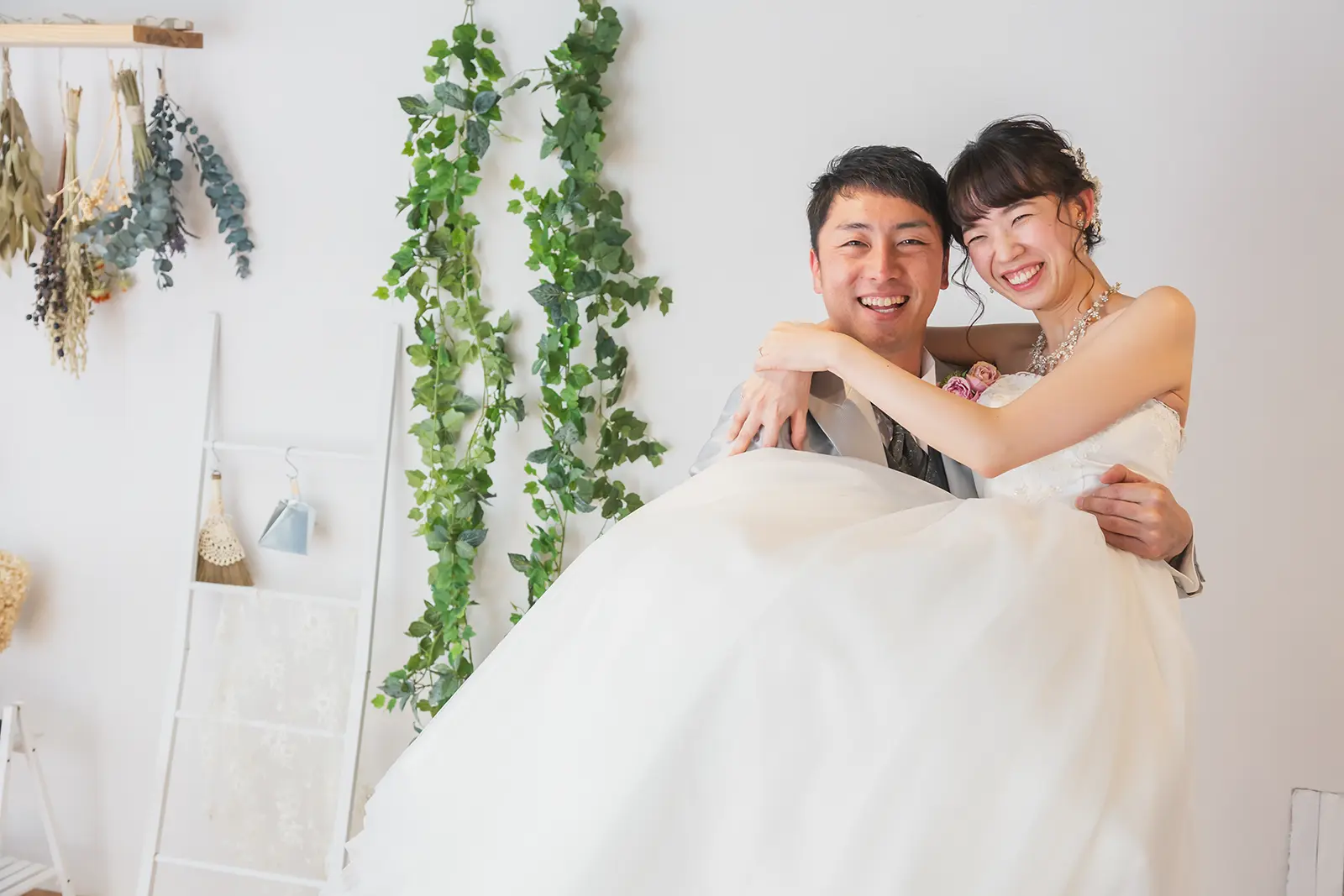新郎が新婦を抱き上げて笑い合うフォトウェディング写真