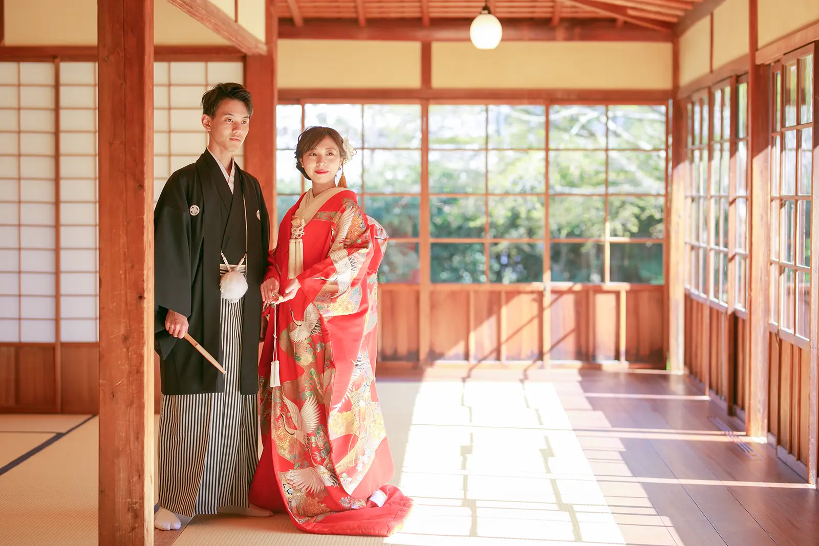 横浜の三溪園の和室回廊で色打掛と紋付袴姿で並ぶ新郎新婦
