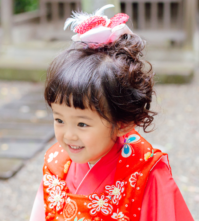 七五三で3歳の女の子の髪型のアップ。ボブ・前髪ありの髪をトップにまとめ、羽根飾りをつけた