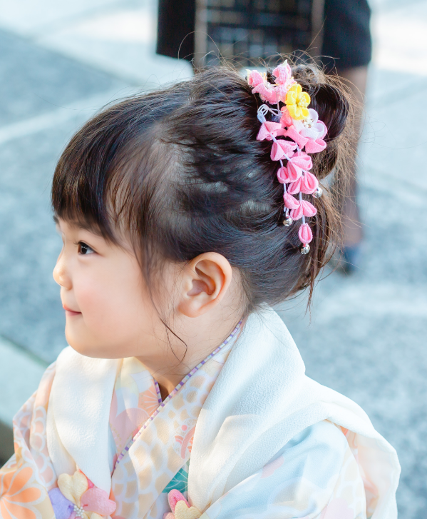 七五三で3歳の女の子の髪型のアップ。前髪ありの髪をサイドにまとめ、下がり飾りをつけた