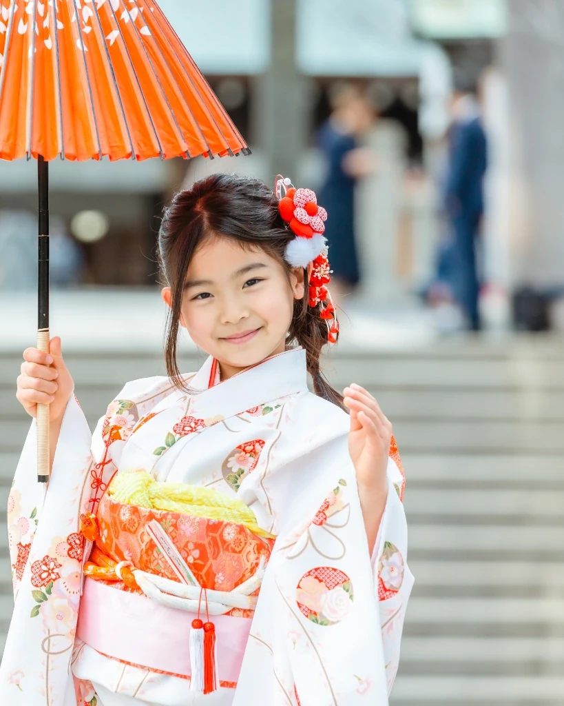 同じ子を正面から。顔まわりに前髪を流し、赤い花飾りの編みおろし