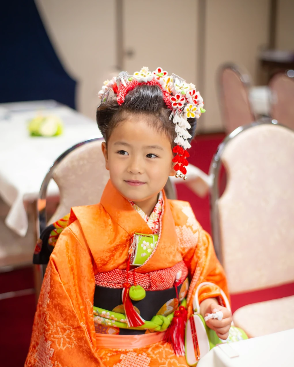 会食の席の七五三7歳の女の子。前髪を高く上げた日本髪風に、大きなつまみ細工の花と白い下がり飾り