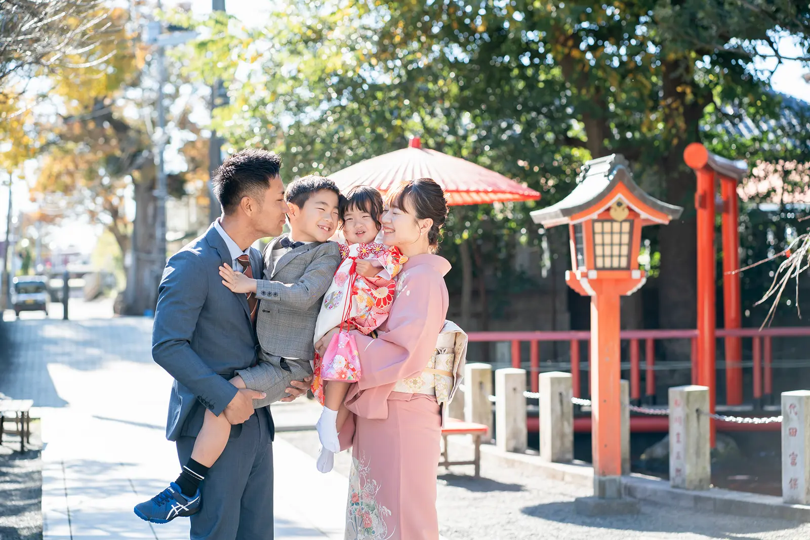 七五三で神社の境内を訪れた家族4人（両親と姉弟）の記念写真